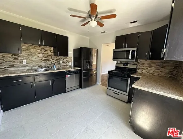 a kitchen with stainless steel appliances kitchen island granite countertop a stove refrigerator and microwave