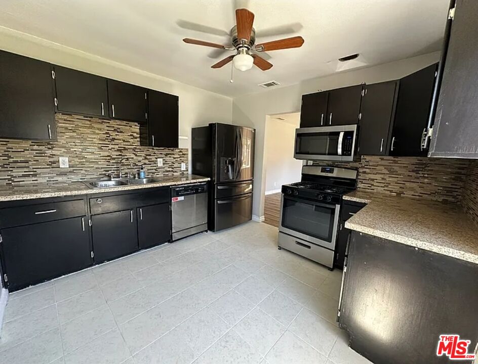 2221 Bataan Road, Unit A Redondo Beach, CA 90278 - Photo 15 of 16 a kitchen with stainless steel appliances kitchen island granite countertop a stove refrigerator and microwave