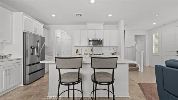 a kitchen with stainless steel appliances granite countertop a refrigerator a sink a stove a dining table and chairs with wooden floor