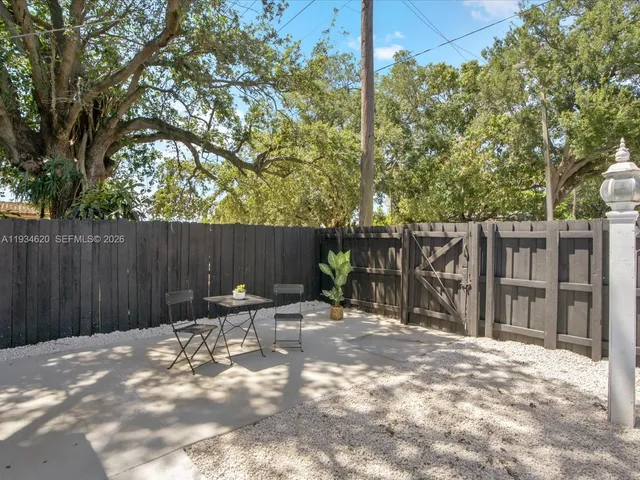 a view of backyard with wooden fence and large trees