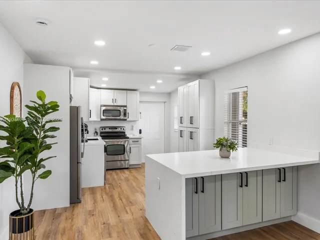 a kitchen with counter top space stainless steel appliances and wooden floor