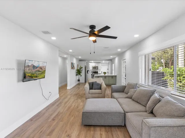 a living room with furniture a ceiling fan and a large window