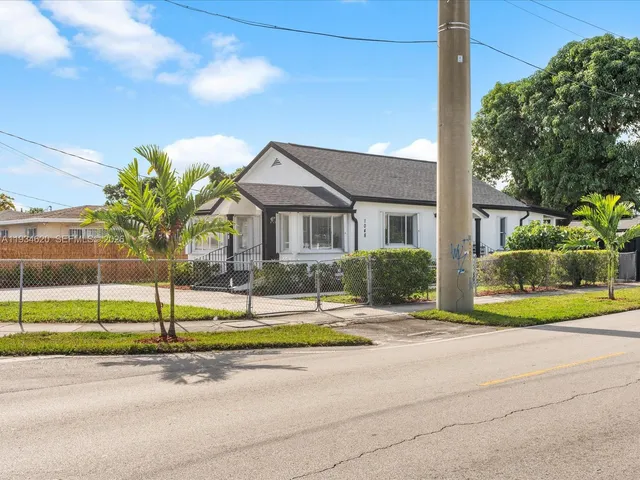 a front view of a house with a yard and potted plants