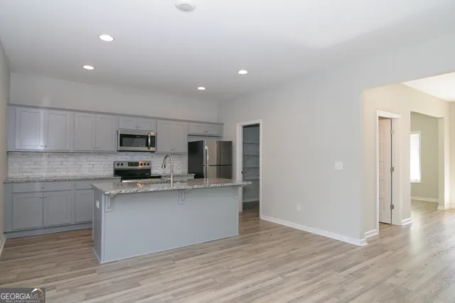 a kitchen with kitchen island granite countertop a sink a stove a microwave and refrigerator