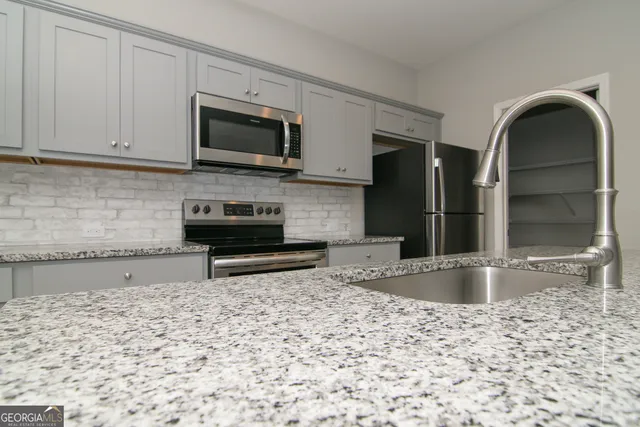 a kitchen with stainless steel appliances granite countertop a stove a sink and a refrigerator