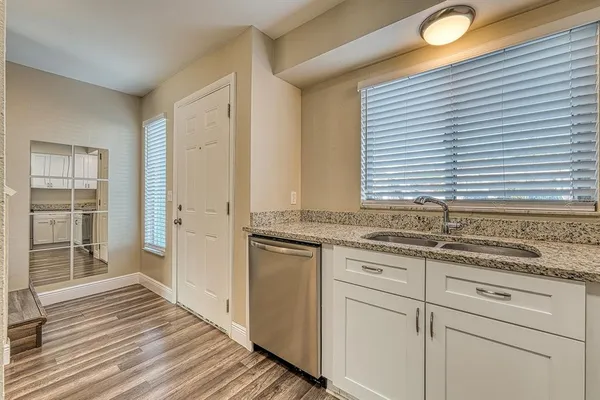 a kitchen with stainless steel appliances granite countertop a sink and cabinets with wooden floor
