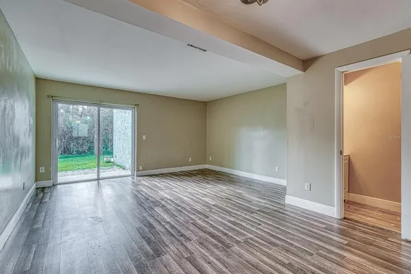 a view of an empty room with wooden floor and a window