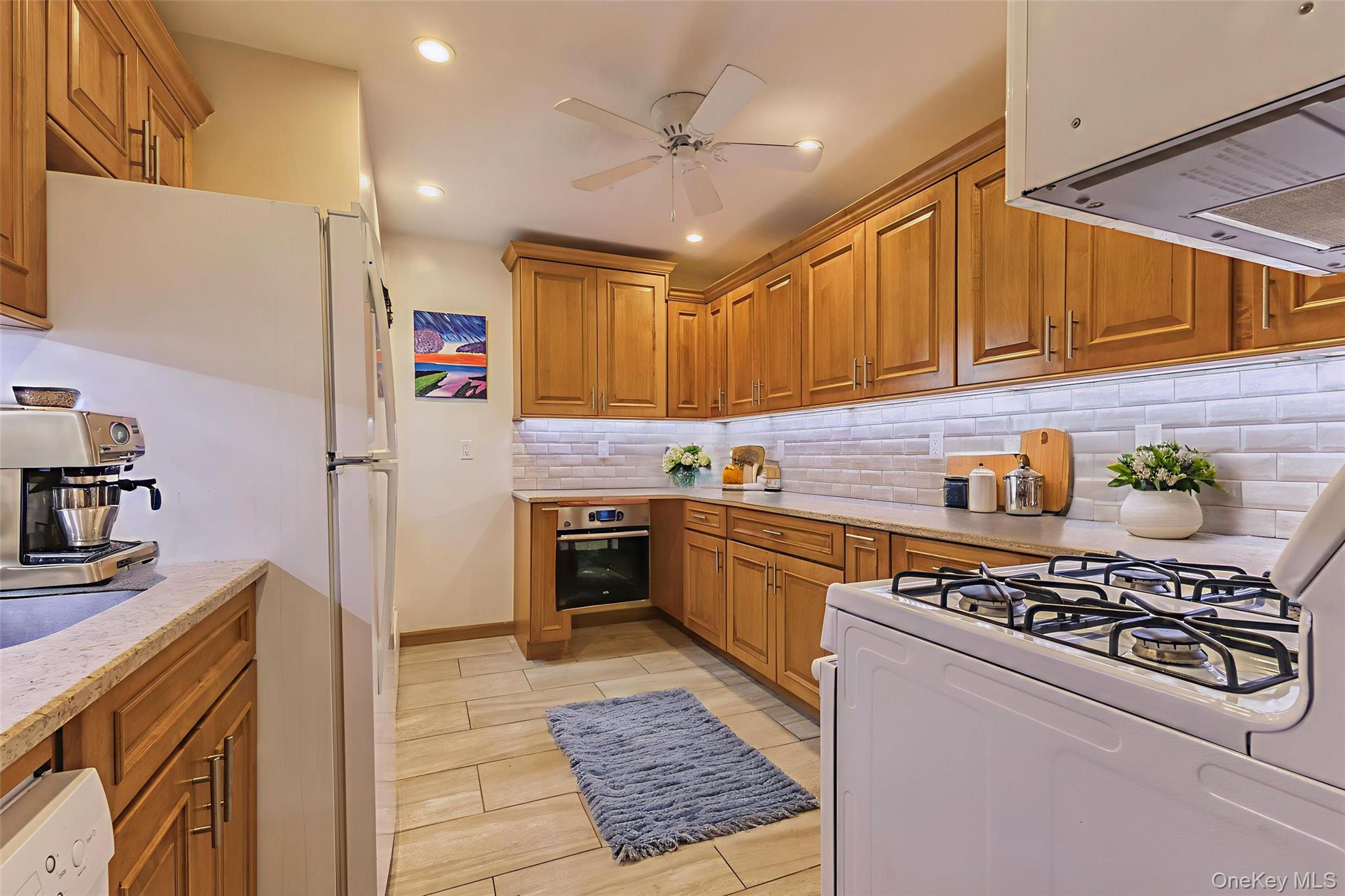 99-10 60th Avenue, Unit 6EE Queens, NY 11368 - Photo 4 of 14 Kitchen with white appliances, brown cabinets, extractor fan, light stone counters, and recessed lighting