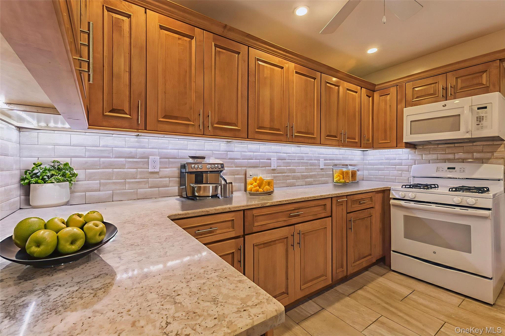 99-10 60th Avenue, Unit 6EE Queens, NY 11368 - Photo 5 of 14 Kitchen with white appliances, brown cabinets, light stone counters, light wood-style floors, and recessed lighting