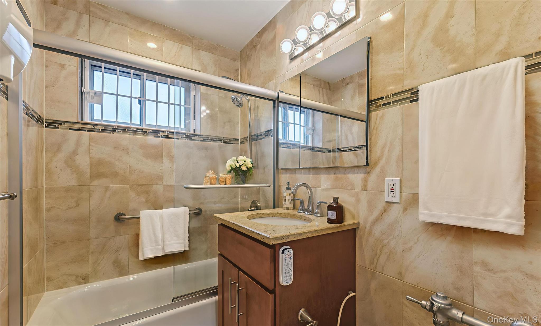 99-10 60th Avenue, Unit 6EE Queens, NY 11368 - Photo 8 of 14 Full bath with enclosed tub / shower combo, vanity, and fully tiled walls