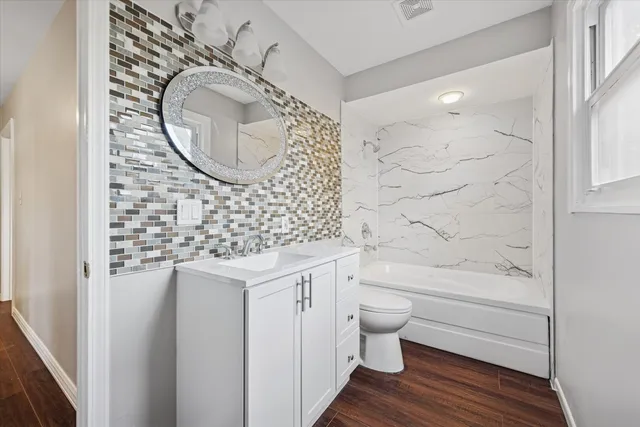 a bathroom with a granite countertop toilet sink and mirror