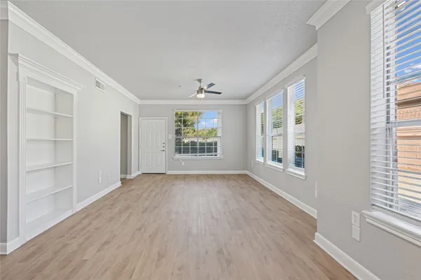 a view of an empty room with a window and wooden floor
