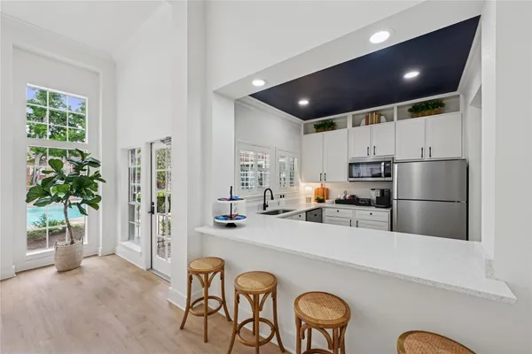 a kitchen with stainless steel appliances a refrigerator a stove a sink a oven with a dining table and chairs