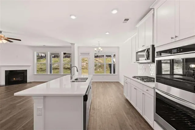 an empty room with wooden floor fireplace and windows