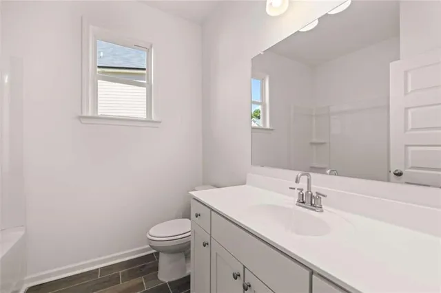 a spacious bathroom with a granite countertop sink a toilet a mirror and shower