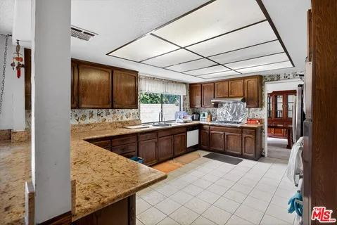a kitchen with stainless steel appliances kitchen island granite countertop wooden cabinets and sink