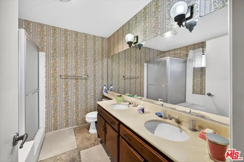 a bathroom with a double vanity sink toilet and shower