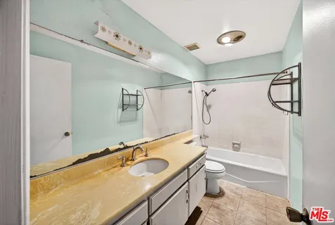a bathroom with a granite countertop sink a toilet and shower
