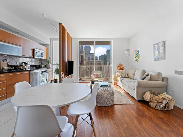 a living room with furniture a large window and wooden floor