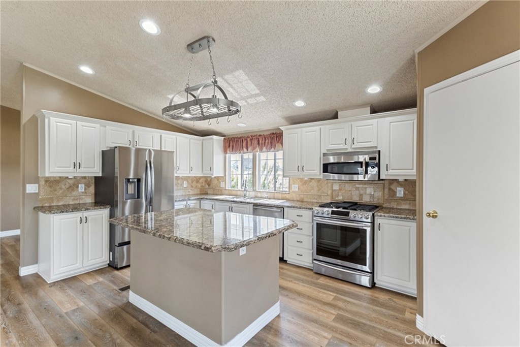 33105 Santiago Road, Unit 149 Acton, CA 93510 - Photo 12 of 28 a kitchen with stainless steel appliances granite countertop a refrigerator oven a sink dishwasher and white cabinets with wooden floor