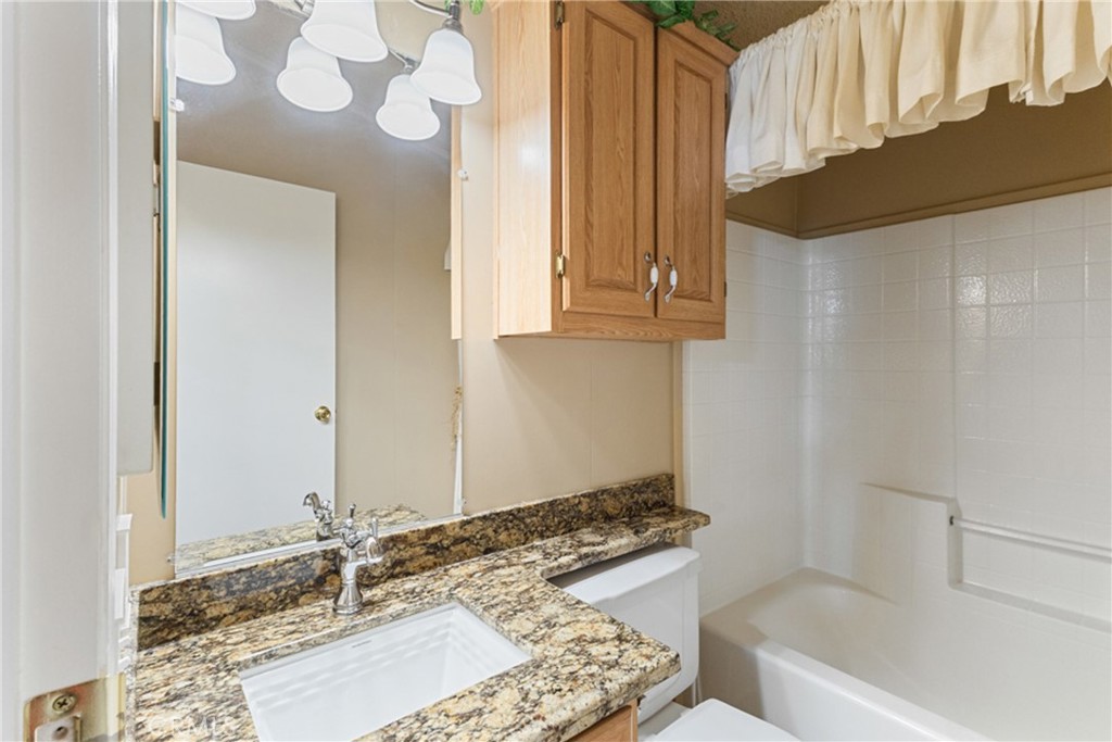 33105 Santiago Road, Unit 149 Acton, CA 93510 - Photo 20 of 28 a bathroom with a granite countertop sink and a mirror