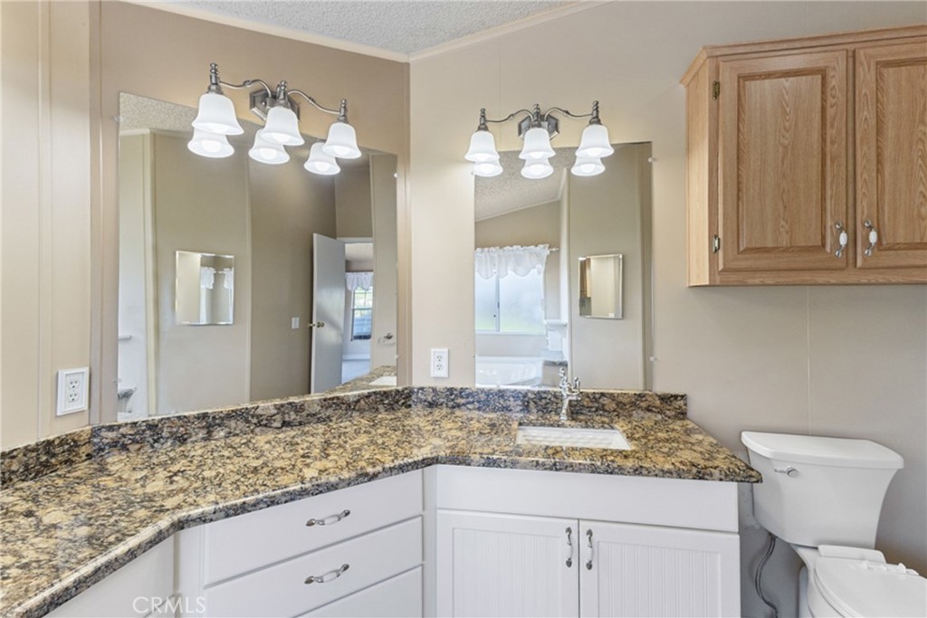 33105 Santiago Road, Unit 149 Acton, CA 93510 - Photo 26 of 28 a bathroom with a granite countertop sink and a mirror