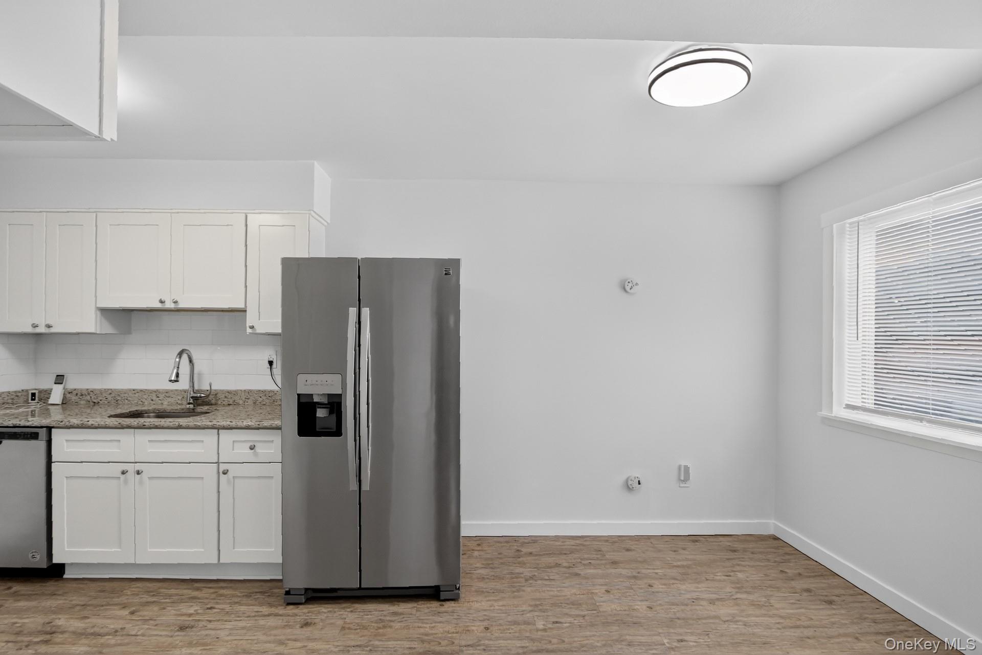 26 Cooper Road, Unit 414 Poughkeepsie, NY 12603 - Photo 16 of 24 Kitchen area featuring white shaker-style cabinetry, a stainless steel side-by-side refrigerator, granite countertops, a subway tile backsplash, and wood-finish flooring