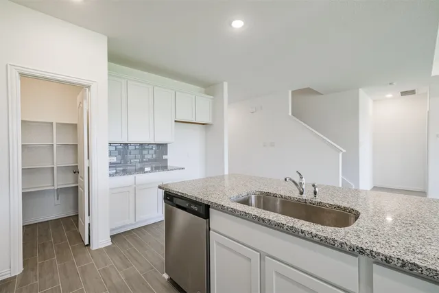 a kitchen with granite countertop a sink a stove and cabinets