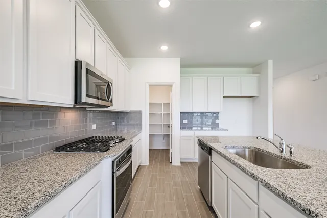 a kitchen with stainless steel appliances granite countertop a sink stove and cabinets
