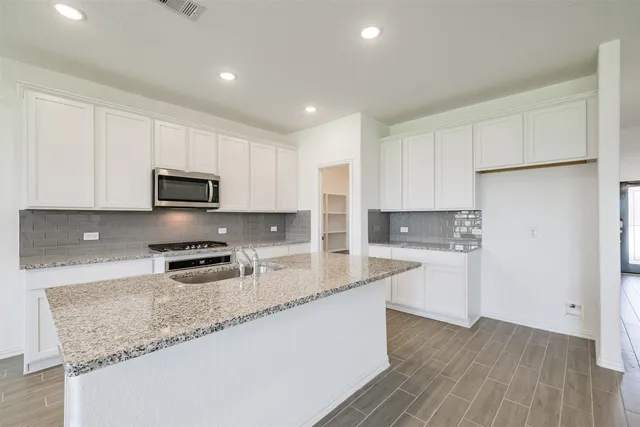 a kitchen with stainless steel appliances granite countertop a stove a sink and a microwave
