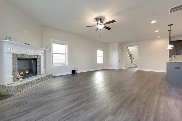 an empty room with wooden floor fireplace and windows