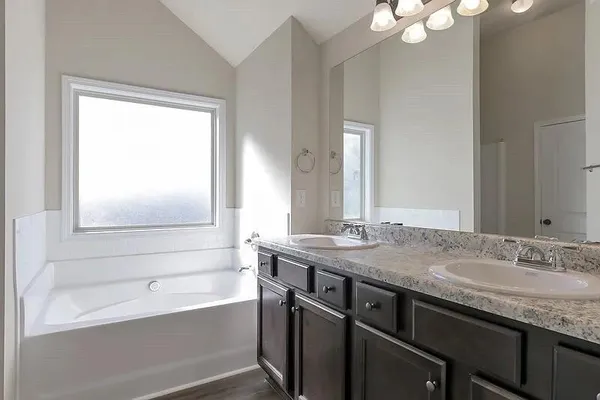 a bathroom with a granite countertop sink a large mirror a bathtub and next to a window