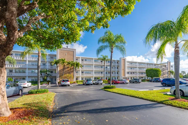 a front view of a building with garden and trees