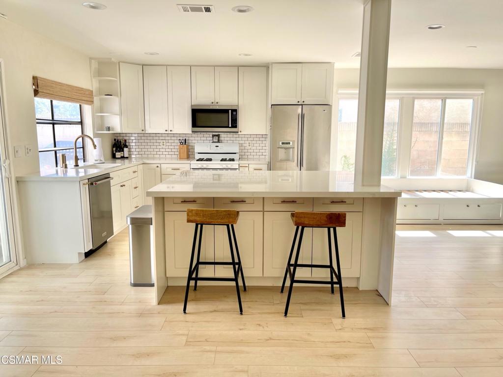 1594 Willowbrook Lane Simi Valley, CA 93065 - Photo 5 of 20 a kitchen with stainless steel appliances kitchen island granite countertop a refrigerator a stove a sink and white cabinets with wooden floor