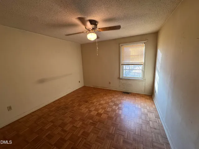 an empty room with a chandelier fan and windows