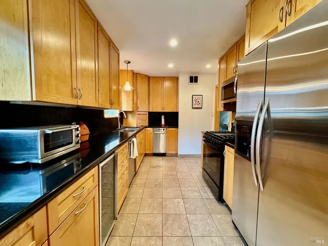 a kitchen with stainless steel appliances a sink a counter top space cabinets and a window