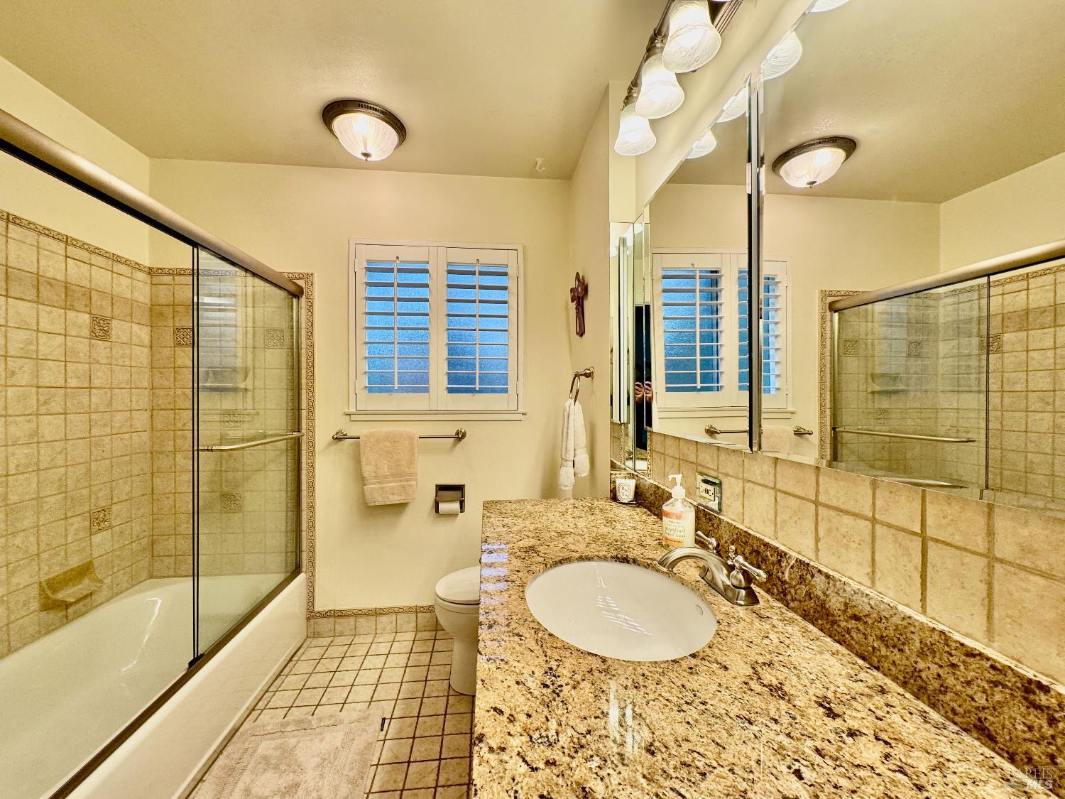 1607 Foothill Boulevard Calistoga, CA 94515 - Photo 17 of 27 a bathroom with a granite countertop sink a mirror a bathtub and shower