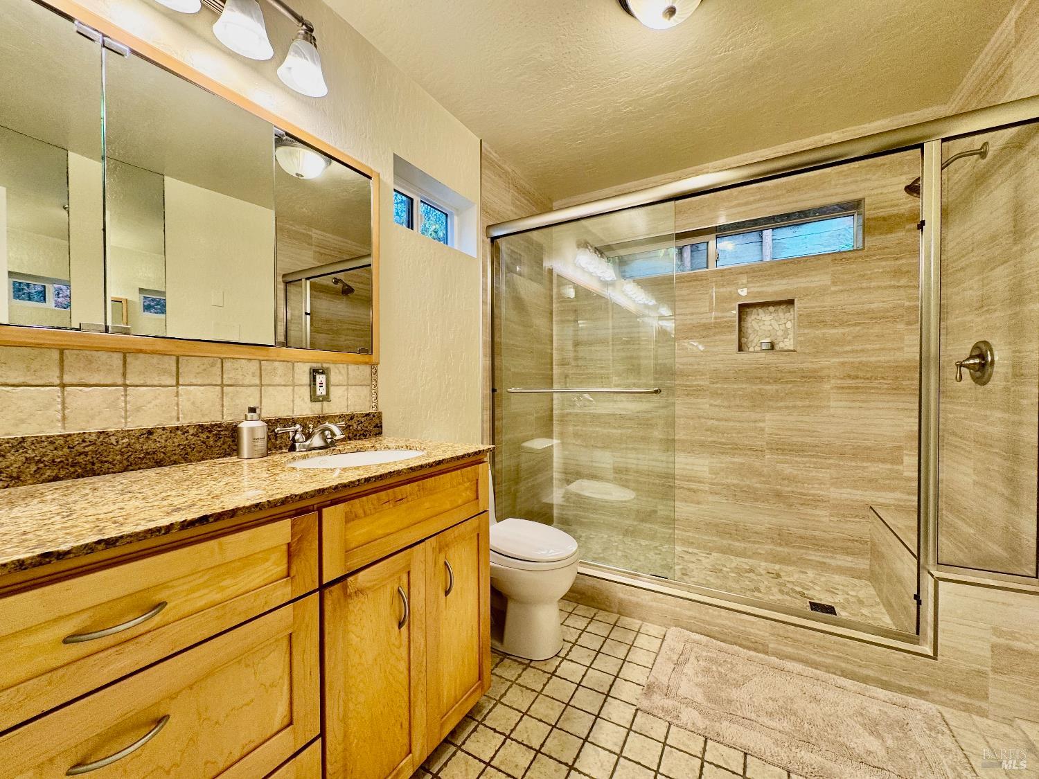 1607 Foothill Boulevard Calistoga, CA 94515 - Photo 21 of 27 a bathroom with a granite countertop sink a toilet a mirror and shower