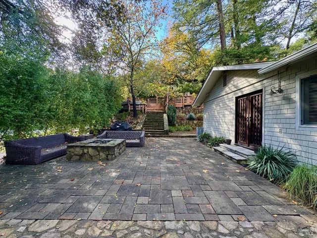 a view of backyard with table and chairs potted plants and large tree