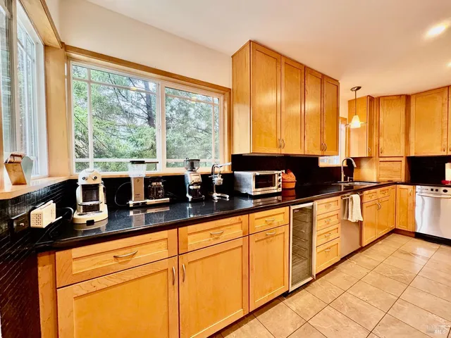 a large kitchen with granite countertop a sink and white cabinets