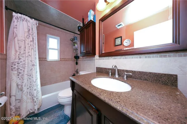 a bathroom with a granite countertop sink a toilet and a mirror