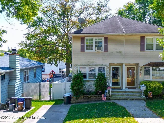 a front view of a house with a yard and potted plants