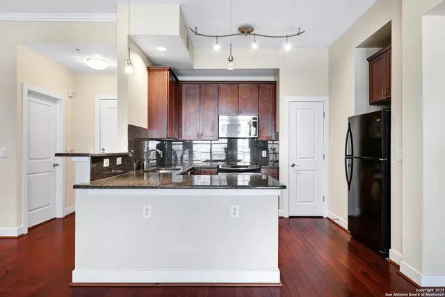 a kitchen with kitchen island a counter top space a sink a refrigerator and a stove