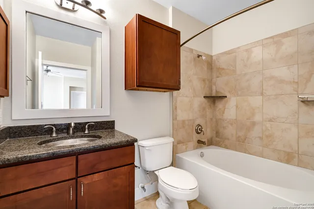 a bathroom with a granite countertop sink a toilet a mirror and bathtub
