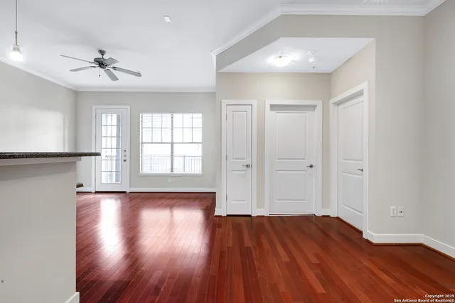 a view of empty room with wooden floor and fan