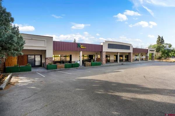 a city street lined with buildings and a cars parked on the side of road