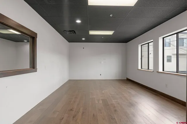 an empty room with wooden floor and windows