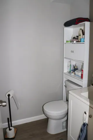 a bathroom with a toilet and a wooden floor