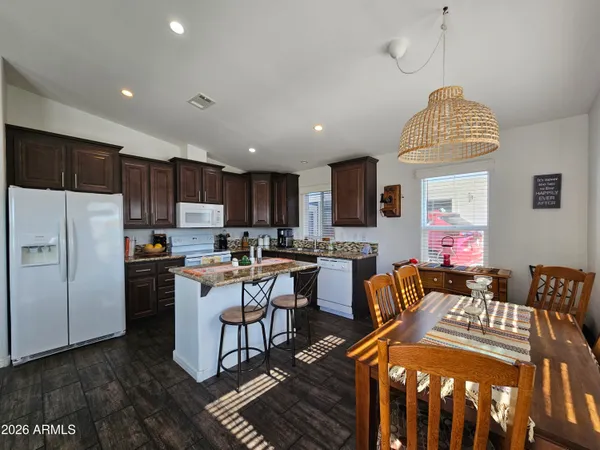 a kitchen with stainless steel appliances granite countertop a stove top oven a sink dishwasher a dining table and chairs with wooden floor