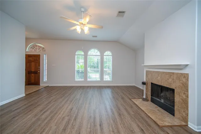 an empty room with wooden floor a fireplace and windows